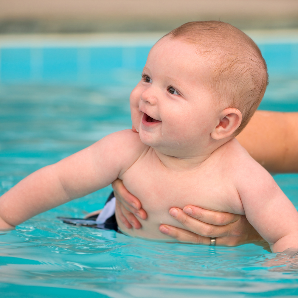 Happy infant baby boy enjoying his first swim in pool ** Note: Shallow depth of field