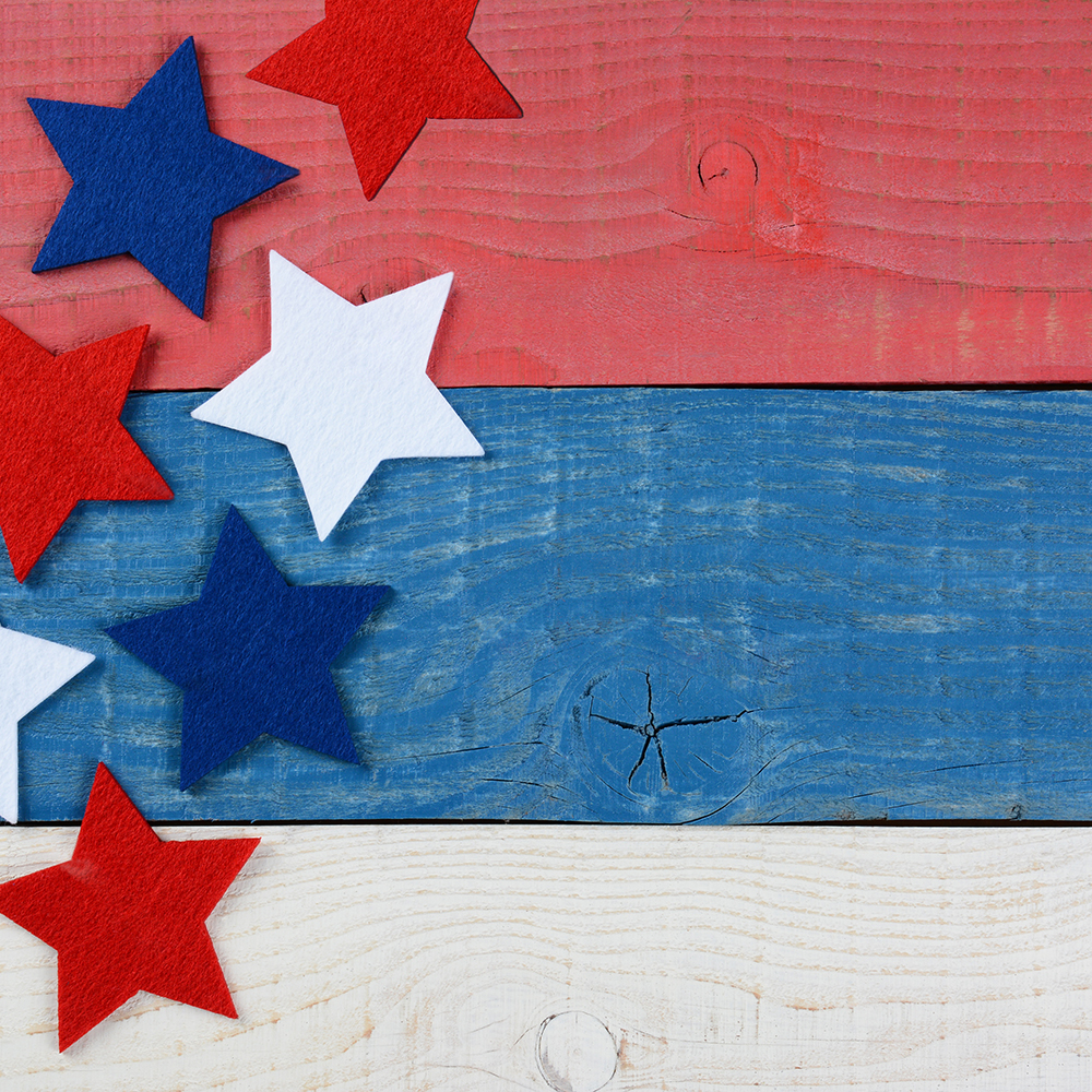 High angle shot of red white and blue stars on a patriotic picnic table. The wood table is painted red, white and blue. Perfect for Memorial Day or 4th of July themes, with copyspace.