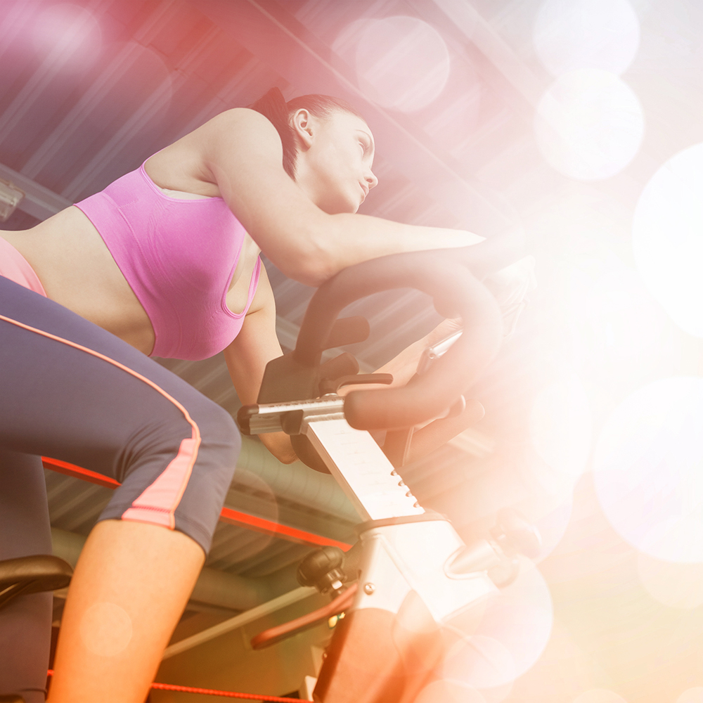 Low angle view of a determined young woman working out at spinning class in gym