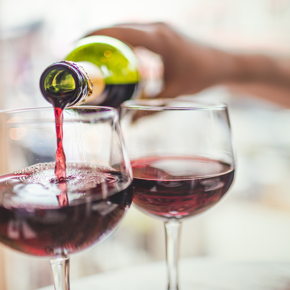 Unrecognizable man pouring red wine in two glasses.