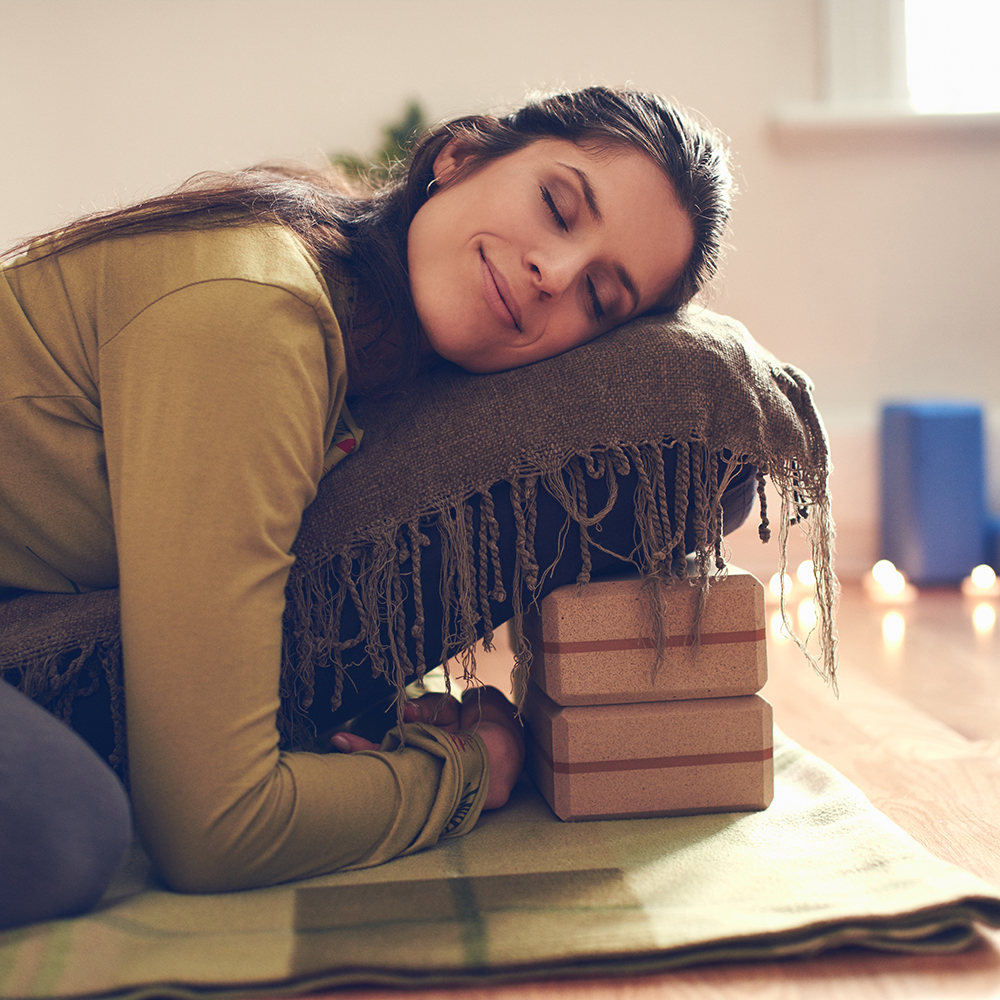 Serene lady relaxing and meditating on a yoga mat in a cosy house
