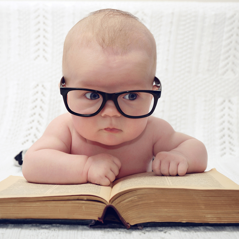 funny portrait of adorable little baby in glasses with old book (thinking expression)