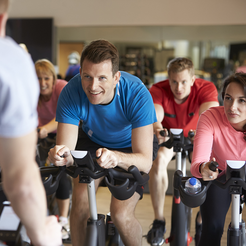 Instructor in foreground with spinning class at a gym