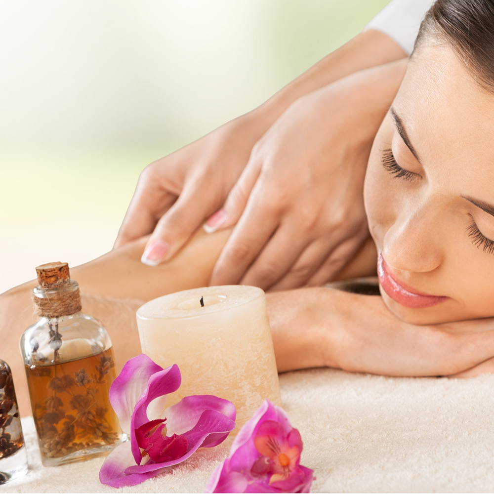 woman receiving massage with flowers and candle on table