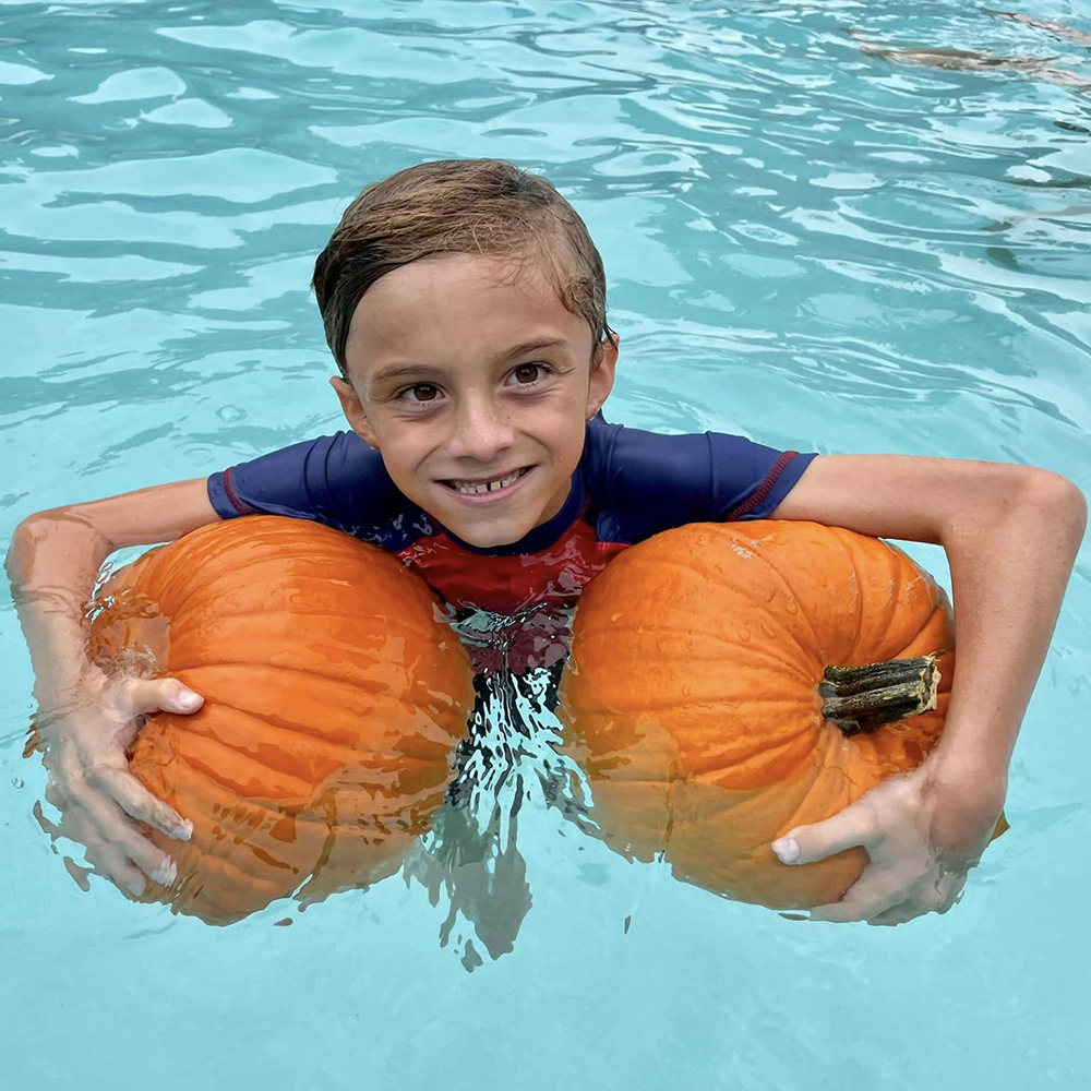 Child holding pumpkins in swimming pool