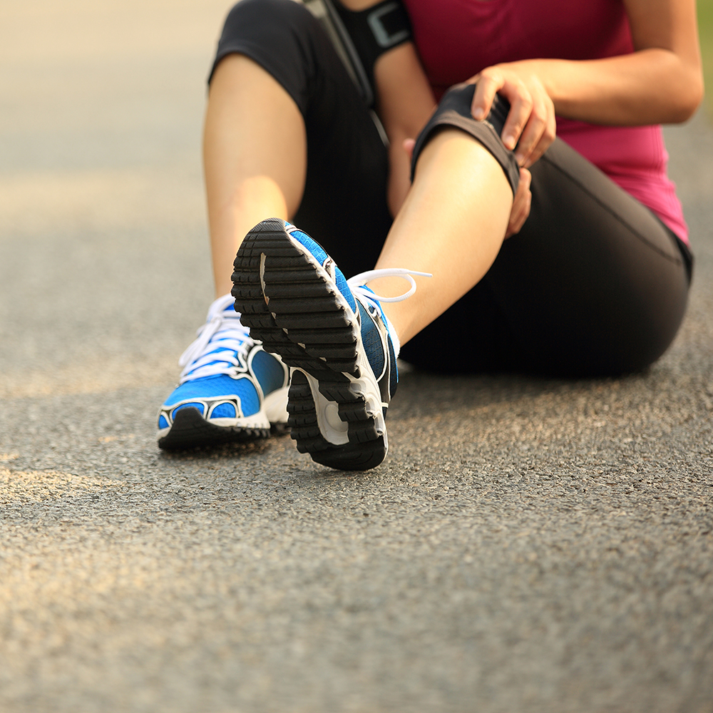 woman sitting in tennis shoes holding painful knee