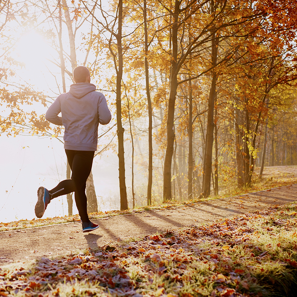 Man running through autumn trees and leaves