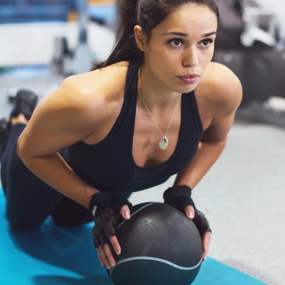 Fit woman exercising with medicine ball workout out arms Exercise training triceps and biceps doing push ups.
