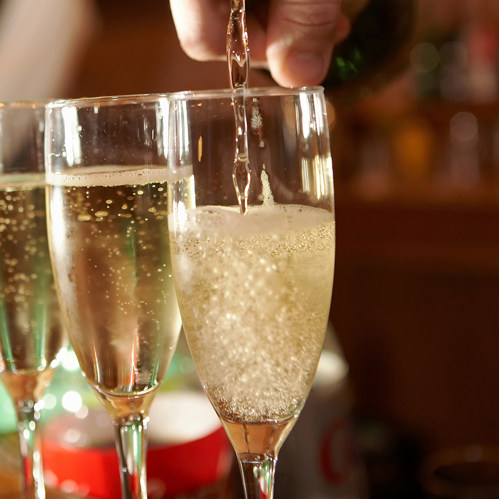 Hand of bartender pouring glasses of champagne