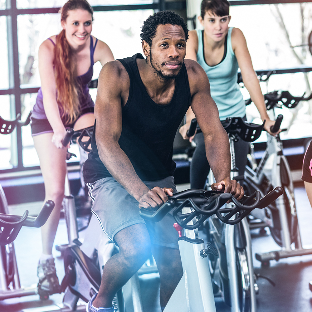 Fit people working out at spinning class in gym