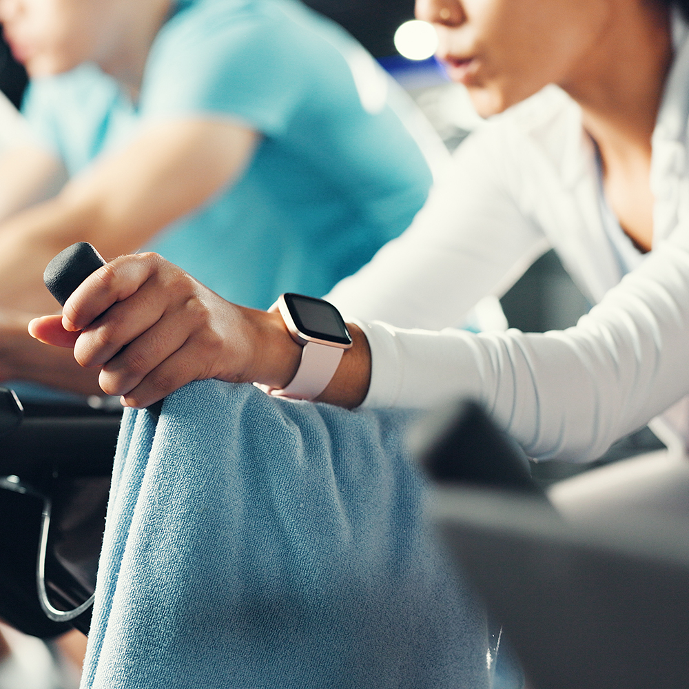 Fitness, exercise class and hands of people in gym on bicycle for cardio exercise, workout and training. Sports machine, health club and group on bike for cycling, endurance and challenge for wellness
