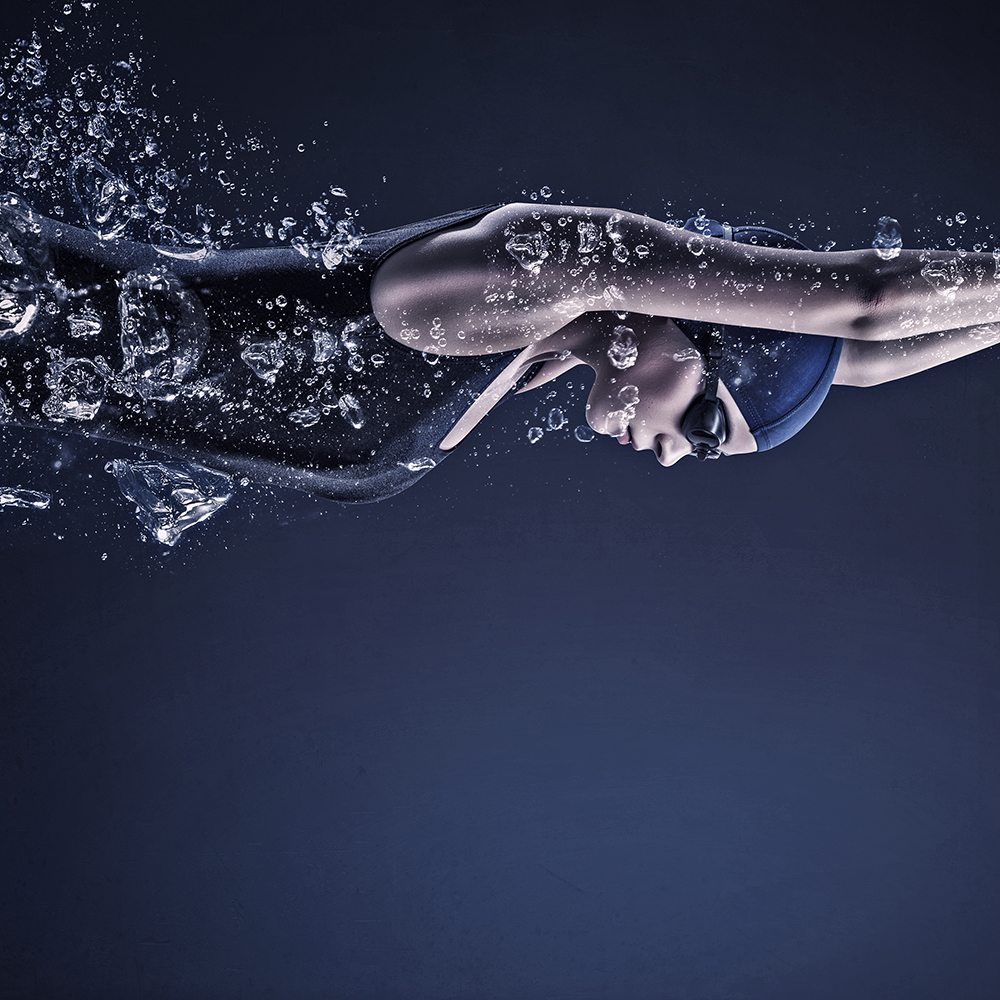 Young woman swimmer in cap and glasses under water