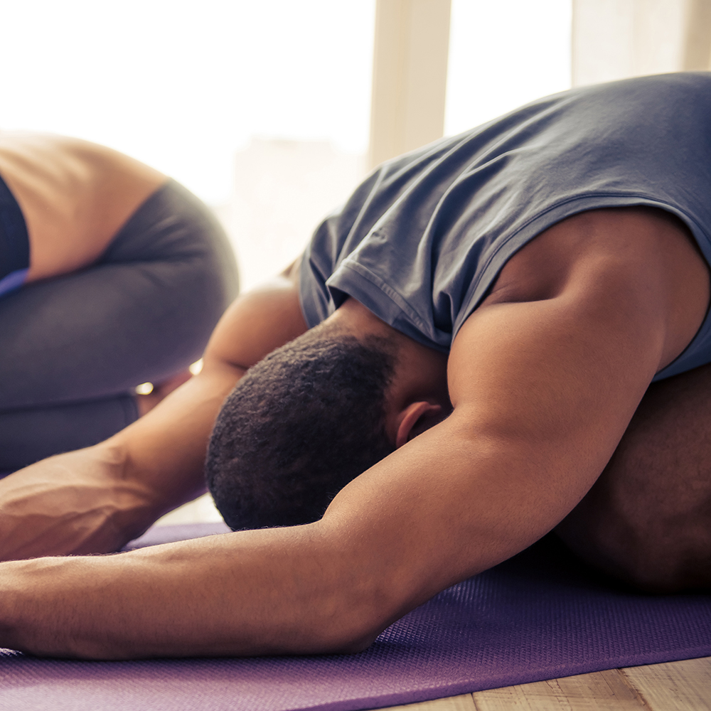 Beautiful Afro American couple in sports clothes is stretching on yoga mat while working out at home
